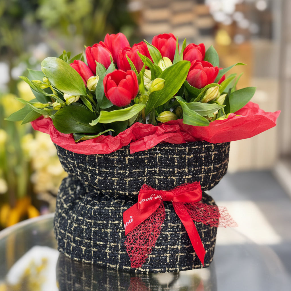 Bouquet of red roses wrapped in black paper with a red ribbon on a blurred background