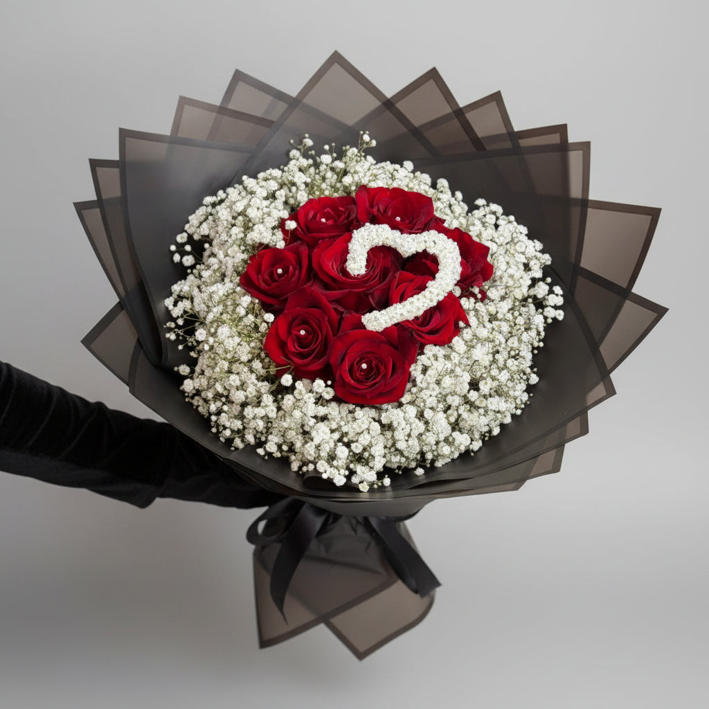 Bouquet of red roses with a heart-shaped arrangement on top, surrounded by baby's breath.